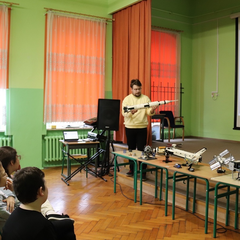 prezenter pokazuje modele z klocków Lego związane z kosmosem