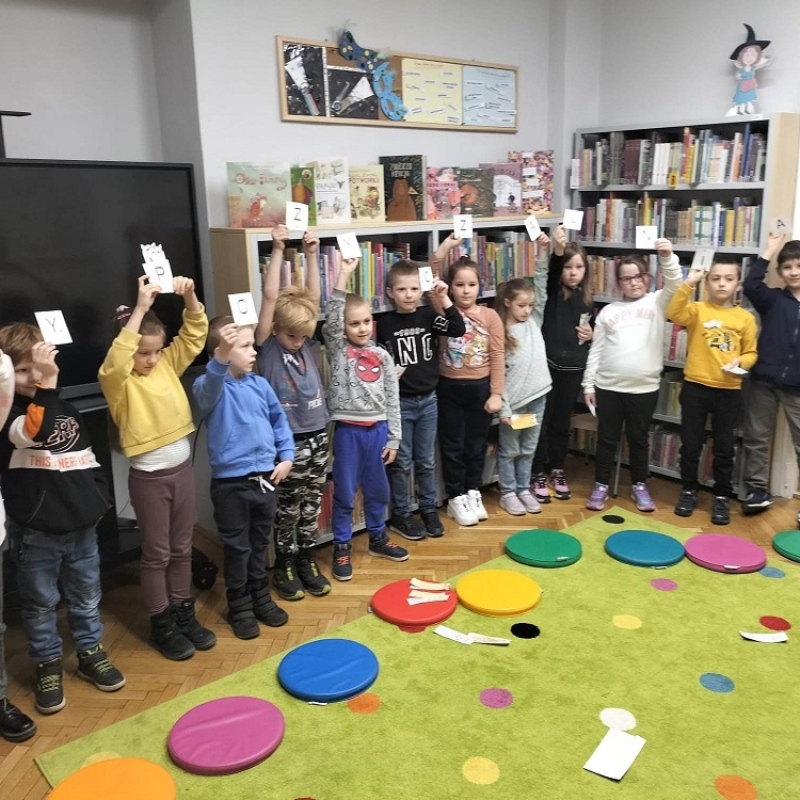 Uczniowie z kartonikami tworzącymi hasło Wypożyczalnia