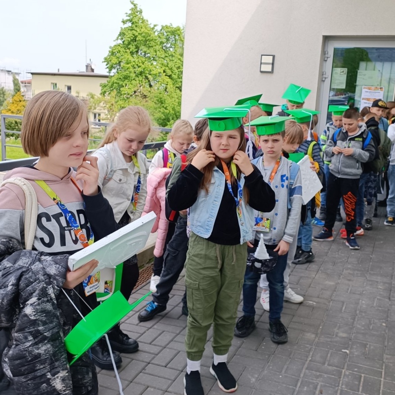 Uczniowie klasy trzeciej w biretach przed budynkiem ATH