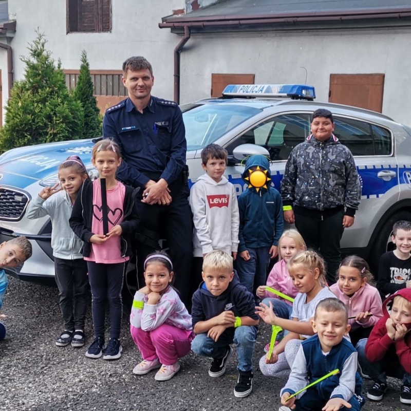 Klasa 1 a z policjantem pozuje przez radiowozem policyjnym