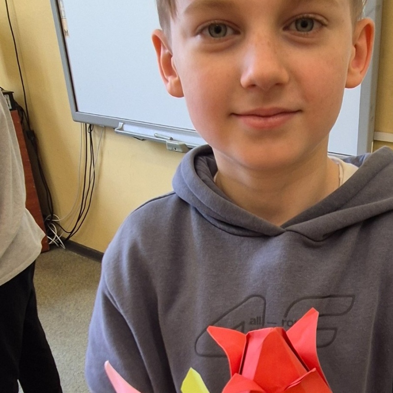 Uczeń klasy 3b pozuje z własnoręcznie zrobionymi tulipanami origami