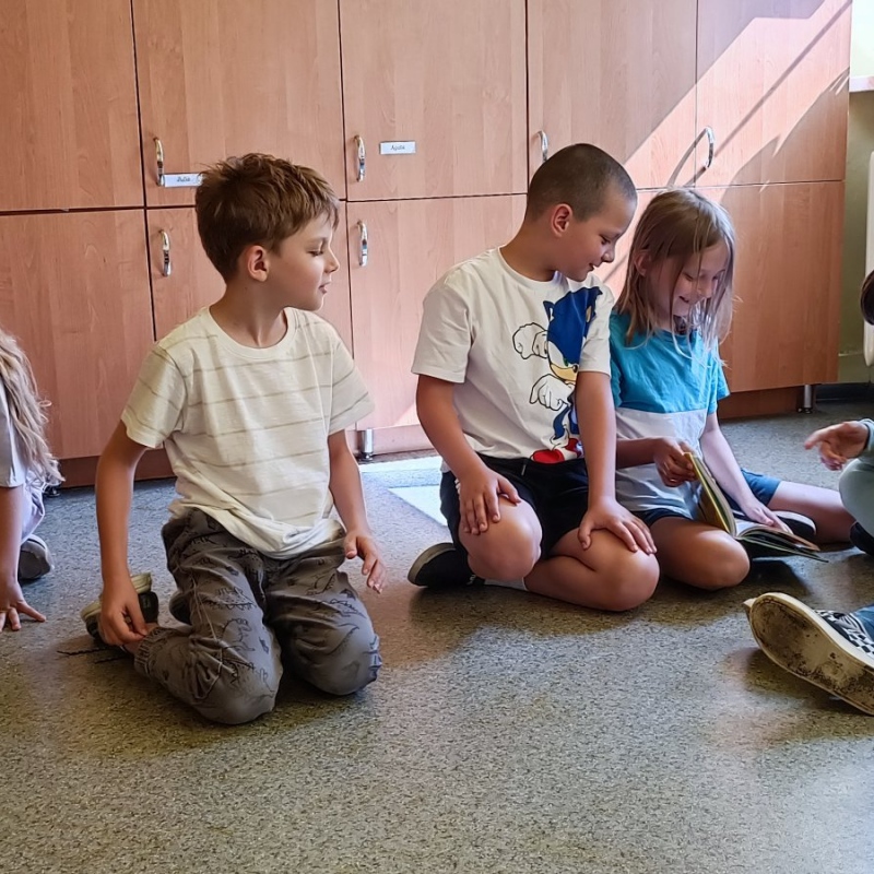 Uczniowie klasy 2 siedzą na podłodze w trakcie spotkania