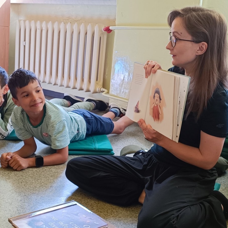 Panie ilustratorka czyta uczniowie słuchają z zaciekawieniem