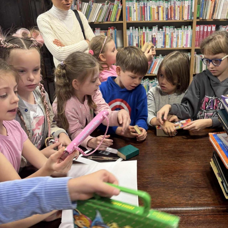 Nauczycielka patrzy na uczniów którzy oglądają książki