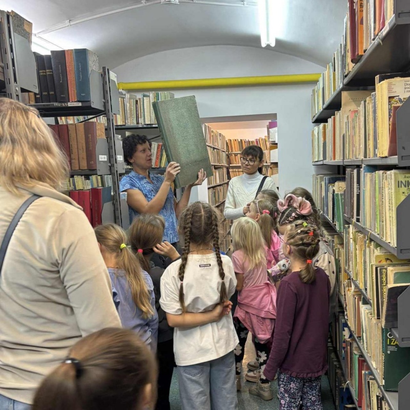 Pani bibliotekarka pokazuje uczniom dużą książkę