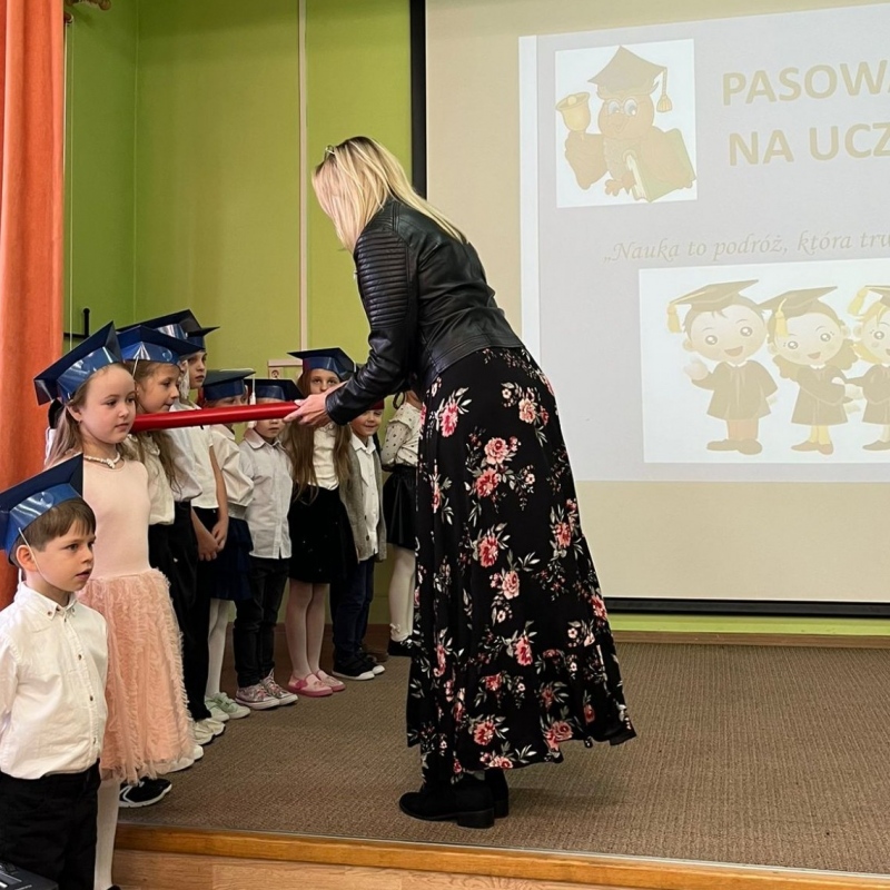 pani dyrektor pasuje na uczniów dzieci stojące na scenie