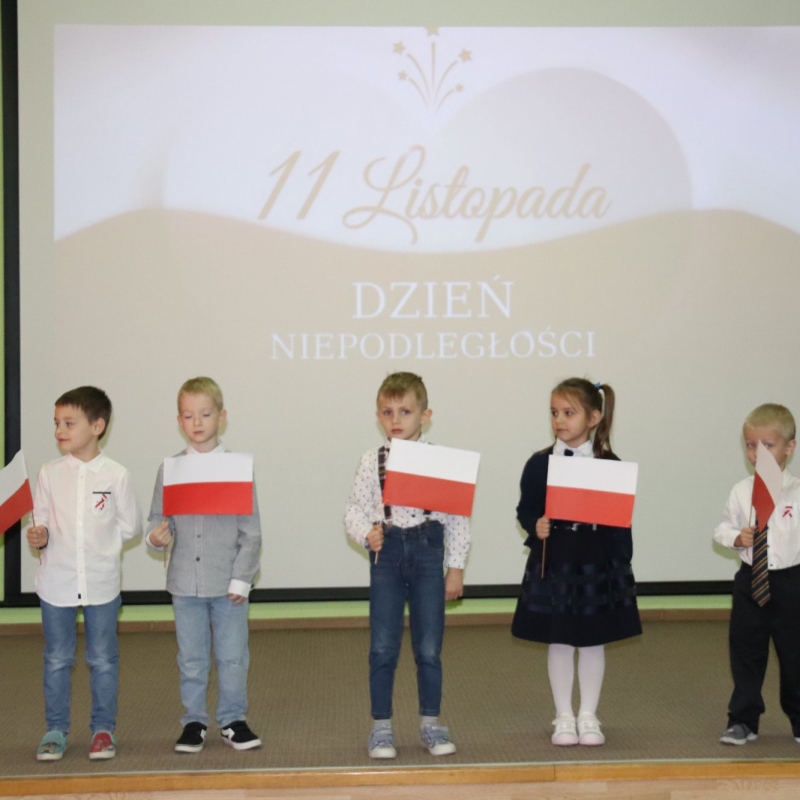 5 uczniów z flagami  na wyświetlanym tle 11 listopada