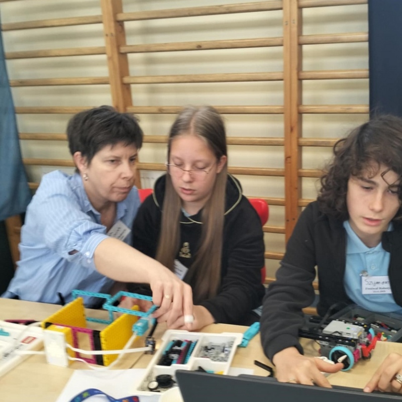 nauczyciel z uczniami buduje konstrukcję z klocków lego