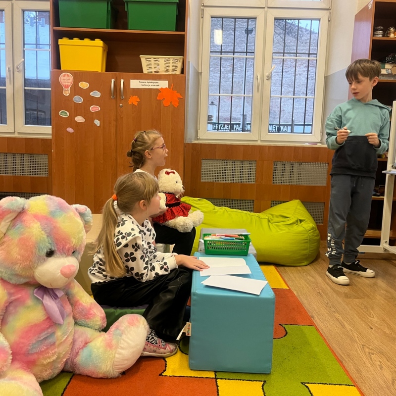 Uczeń przy tablicy na świetlicy misie i inni uczniowie siedzą