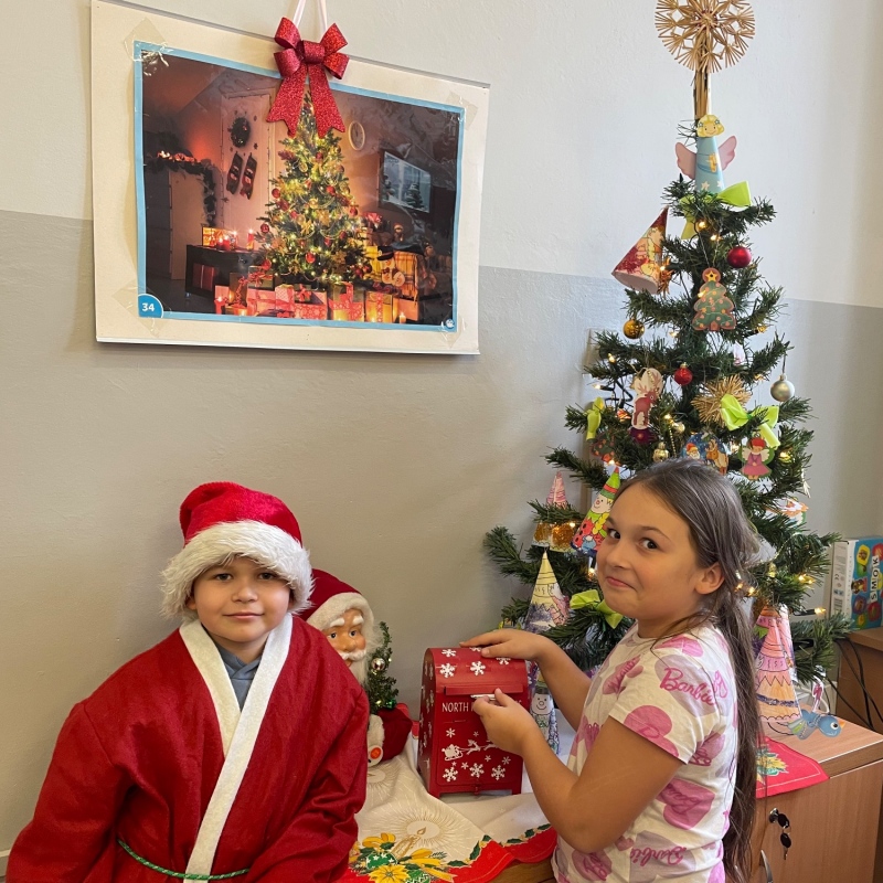 Uczniowie przy skrzynce na listy do Mikołaja w sali i choince jeden uczeń w stroju Mikołaja