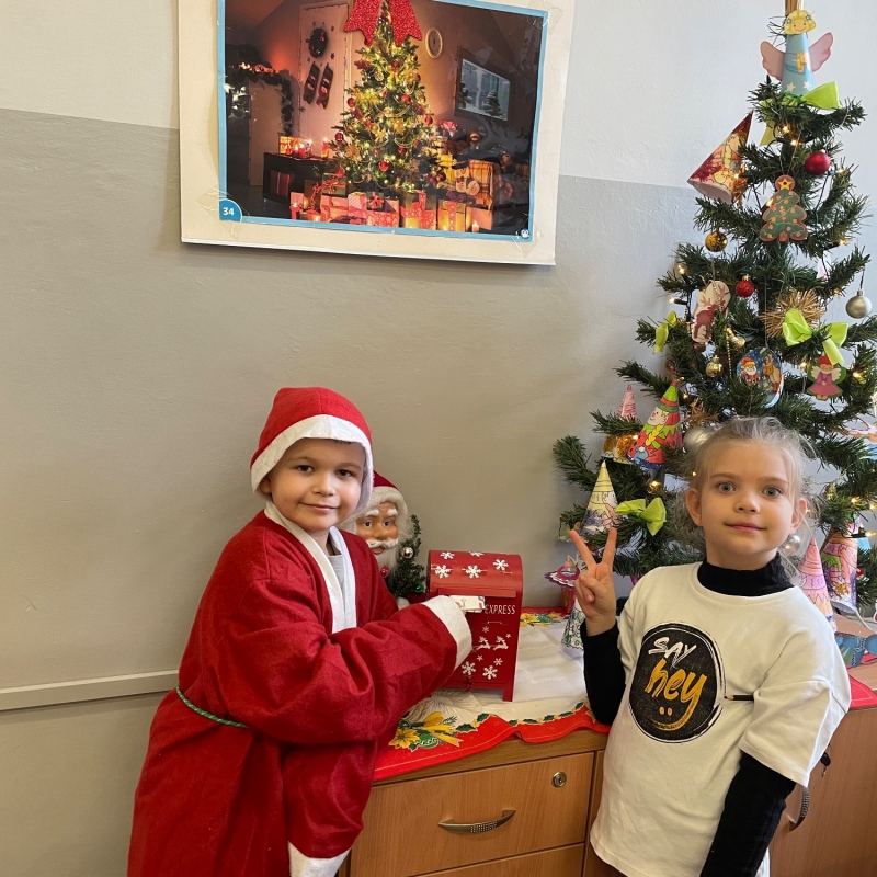 Uczniowie przy skrzynce na listy do Mikołaja w sali i choince jeden uczeń w stroju Mikołaja