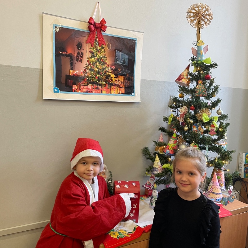 Uczniowie przy skrzynce na listy do Mikołaja w sali i choince jeden uczeń w stroju Mikołaja