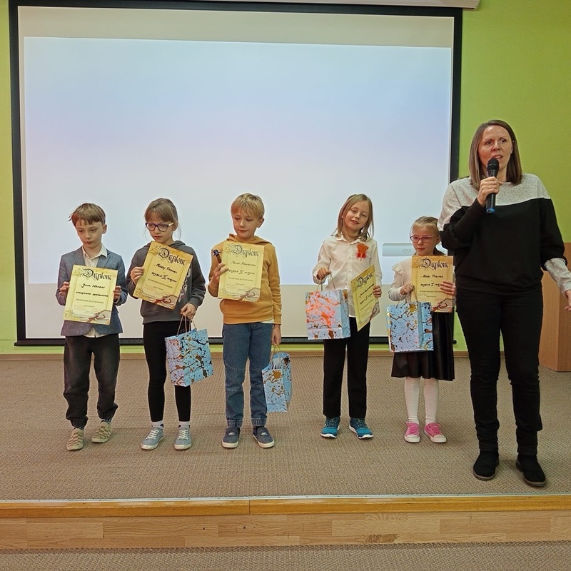 zwycięska grupa uczniów na scenie z dyplomami i przewodniczącą jury