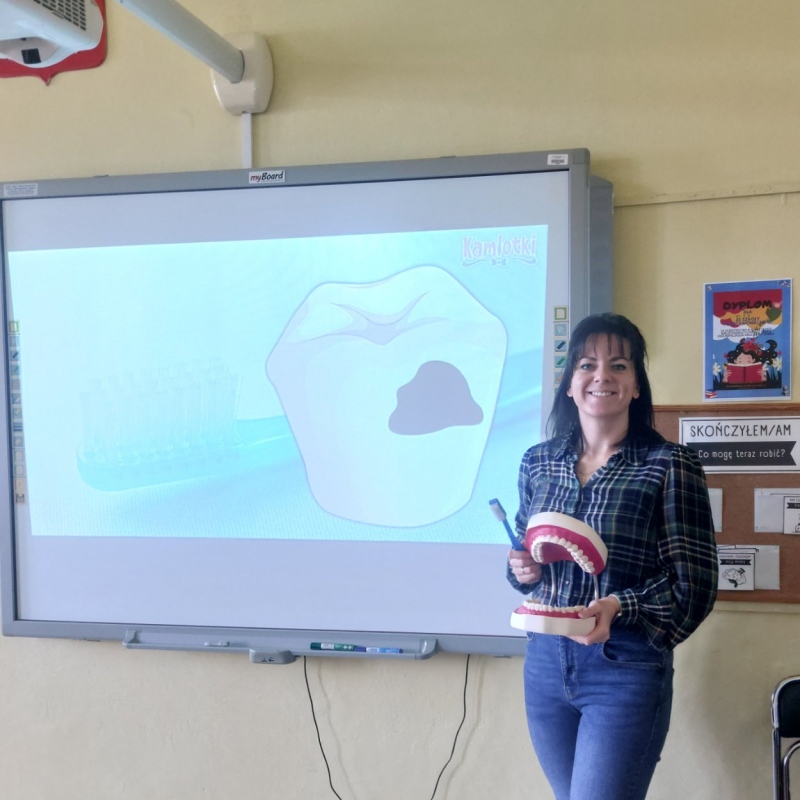 Nauczycielka przy tablicy z pomocami dydaktycznymi
