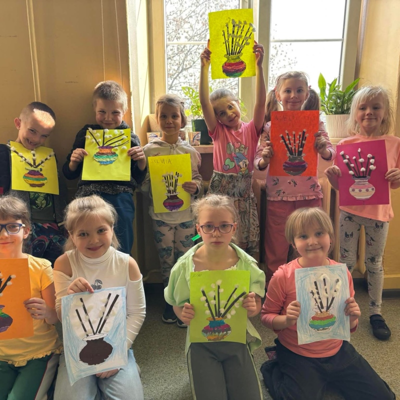 uczniowie z obrazkami ilustrującymi wiosnę