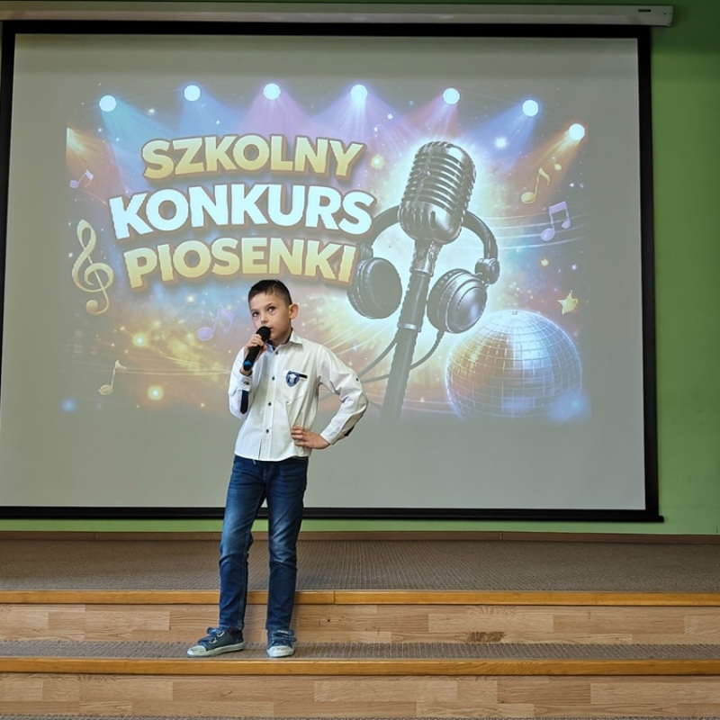 dziecko śpiewające na tle baneru szkolny konkurs piosenki