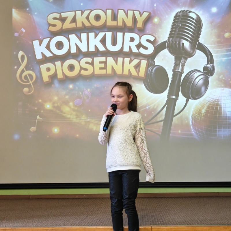 dziecko śpiewające na tle baneru szkolny konkurs piosenki