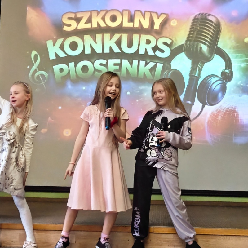 dziecko śpiewające na tle baneru szkolny konkurs piosenki