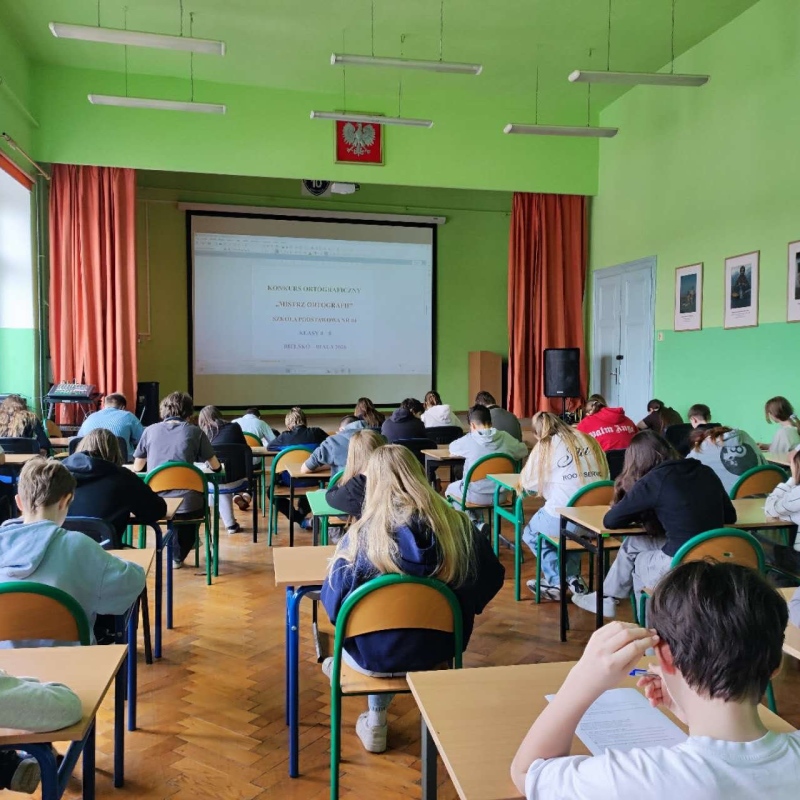 uczniowie w szkolnej auli piszący pracę konkursową