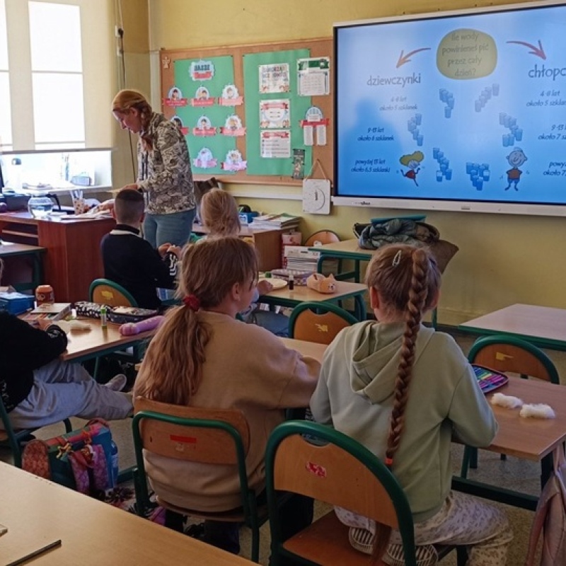 uczniowie w ławkach tworzą pracę plastyczną na papierowych tackach
