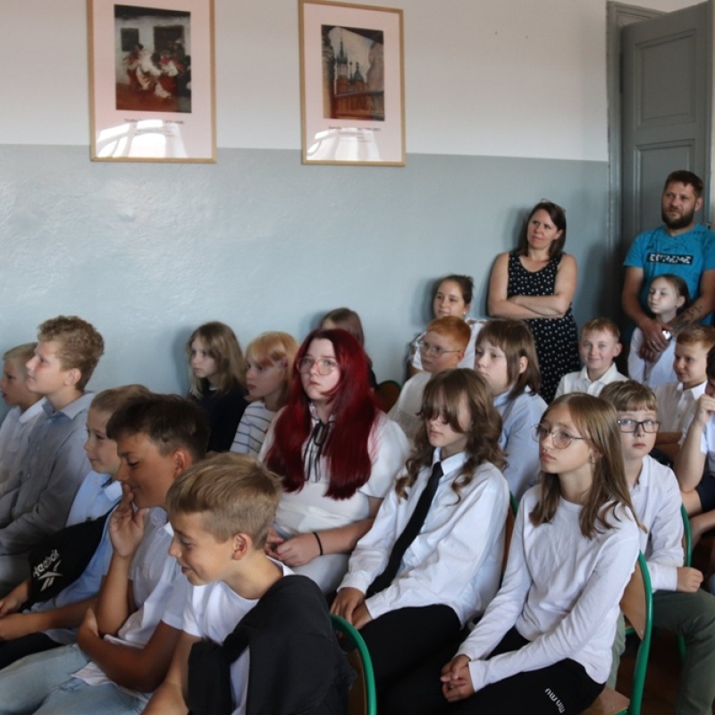 uczniowie z rodzicami na auli szkolnej w galowych strojach