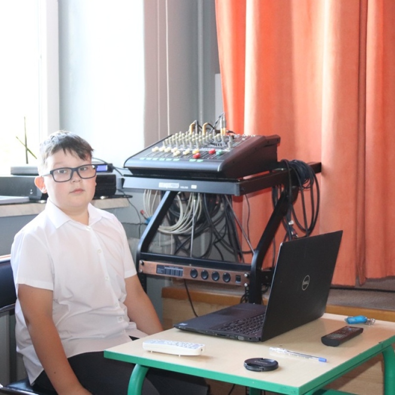 uczeń przy laptopie w stroju galowym