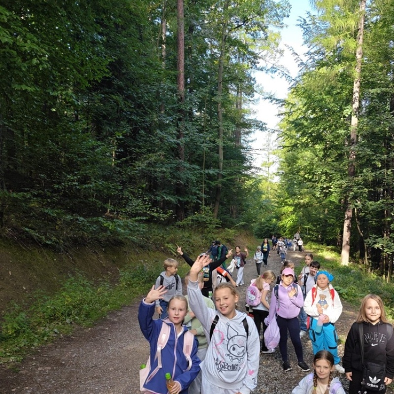 uczniowie na leśniej ścieżce machają