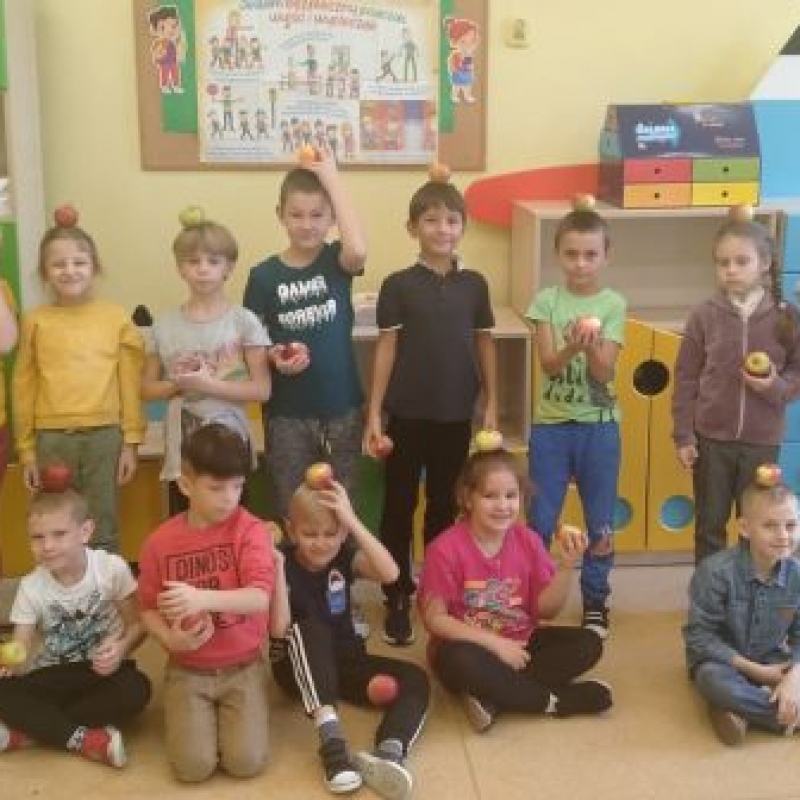 dzieci trzymające jabłka na głowie